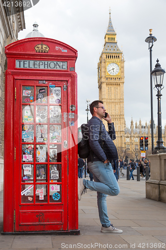 Image of Man talking on mobile phone, red telephone box and Big Ben. London, England