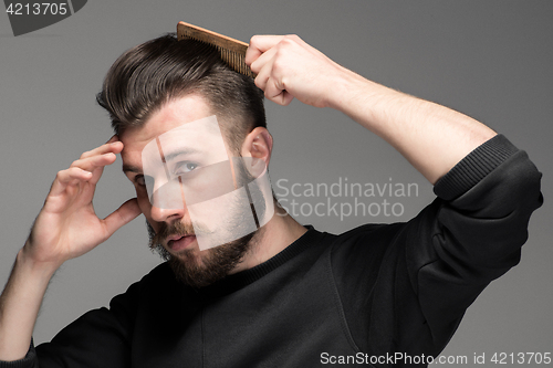 Image of Portrait of stylish handsome young man combing his hair