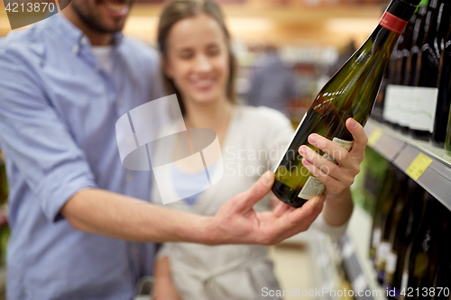 Image of happy couple with bottle of wine at liquor store