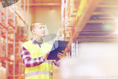 Image of man with clipboard in safety vest at warehouse