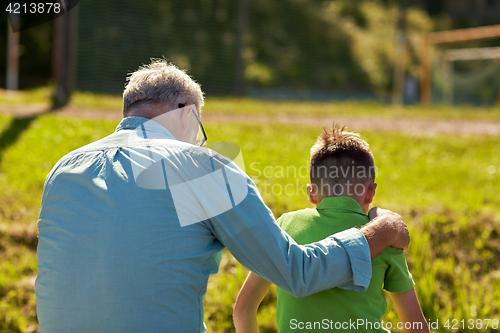 Image of grandfather and grandson hugging outdoors