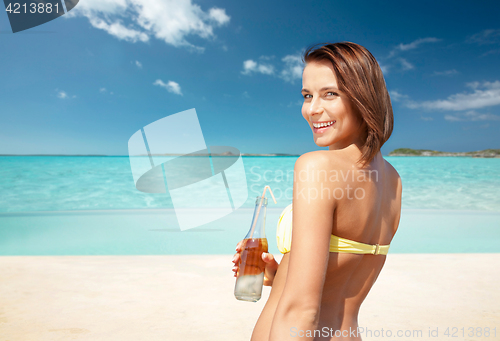 Image of woman in bikini with bottle of drink on beach