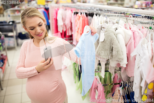 Image of pregnant woman taking picture of baby clothes