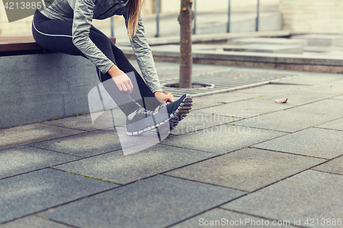 Image of close up of sporty woman tying shoes outdoors