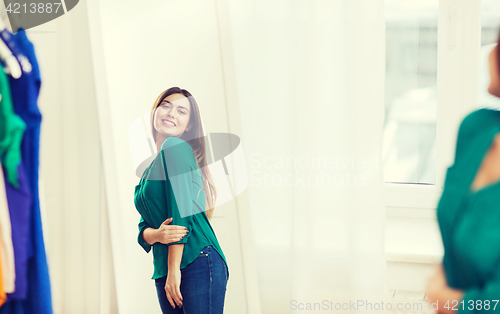 Image of happy woman posing at mirror in home wardrobe