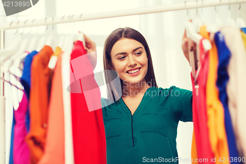 Image of happy woman choosing clothes at home wardrobe