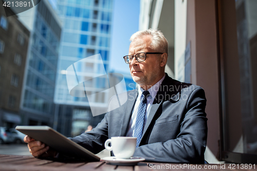 Image of senior businessman with tablet pc drinking coffee