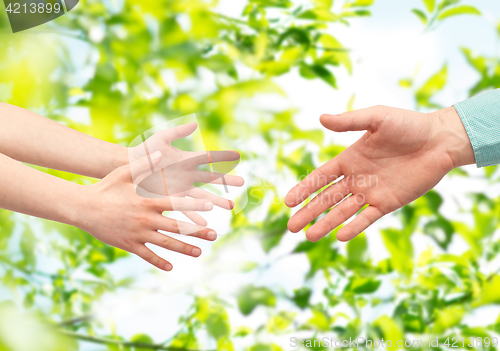 Image of father and child hands over green leaves