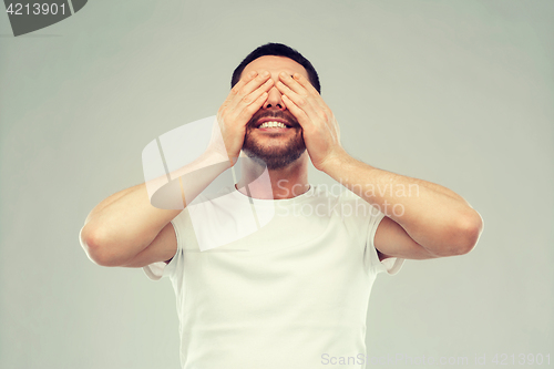 Image of smiling man closing his eyes over gray background