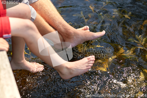 Image of grandfather and grandson sitting on river berth