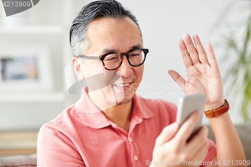 Image of happy man having video call on smartphone at home