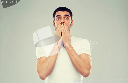 Image of scared man in white t-shirt over gray background