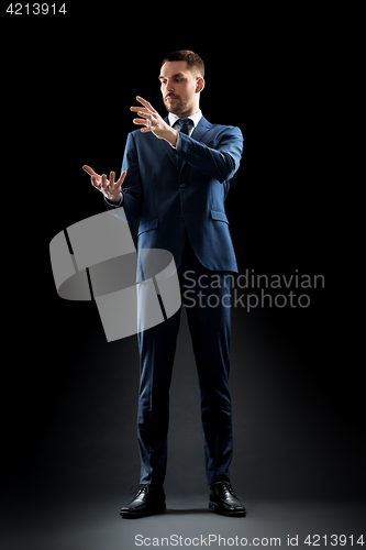 Image of businessman in suit touching something invisible