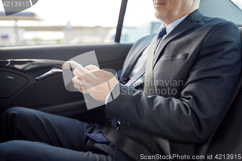 Image of senior businessman texting on smartphone in car