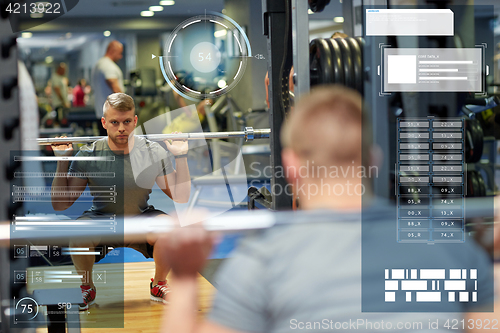 Image of young man flexing muscles with barbell in gym