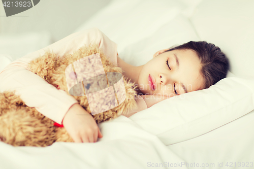 Image of girl sleeping with teddy bear toy in bed at home