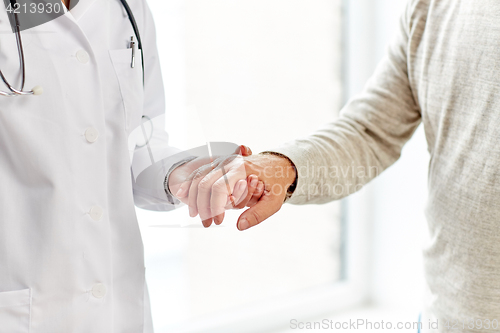 Image of close up of doctor holding old man hand