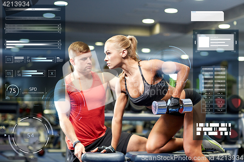 Image of young couple with dumbbell flexing muscles in gym