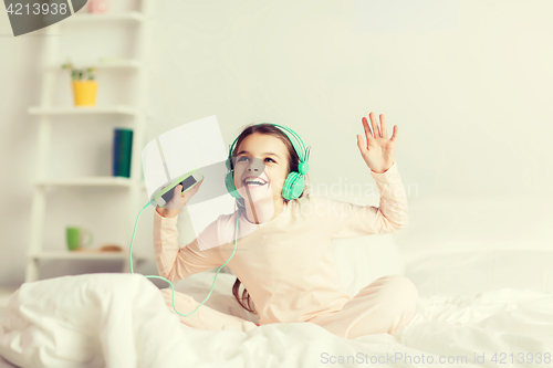Image of girl sitting on bed with smartphone and headphones