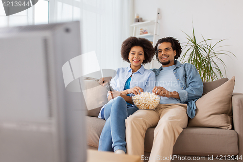 Image of smiling couple with popcorn watching tv at home