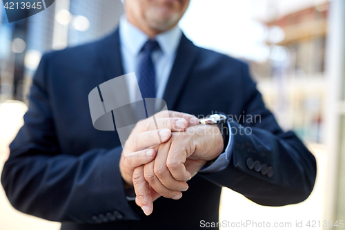 Image of senior businessman with wristwatch on city street