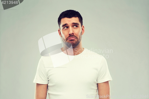 Image of unhappy young man over gray background