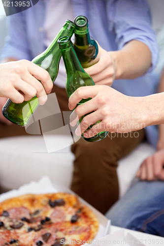 Image of close up of friends clinking beer bottles at home