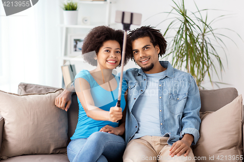 Image of happy couple with smartphone taking selfie at home