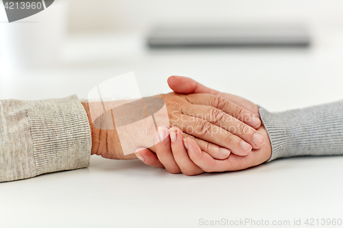 Image of close up of old man and young woman holding hands