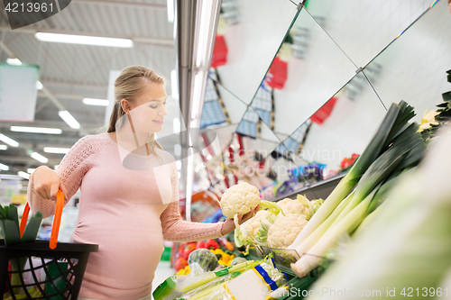 Image of happy pregnant woman buying cauliflower at grocery