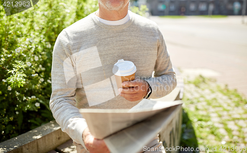 Image of senior man with coffee reading newspaper outdoors