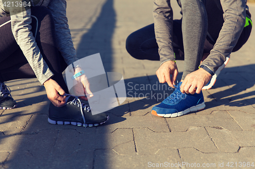 Image of close up of couple tying shoelaces outdoors