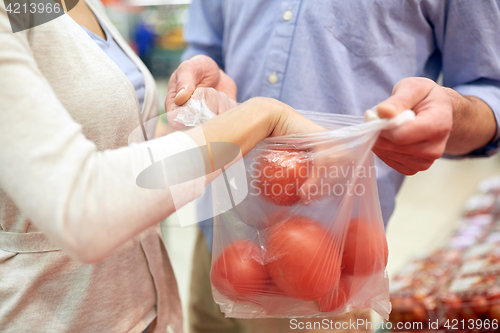 Image of close up of couple with tomatoes at grocery store