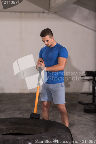 Image of man workout with hammer and tractor tire