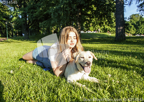 Image of young attractive blond woman playing with her dog in green park at summer, lifestyle people concept