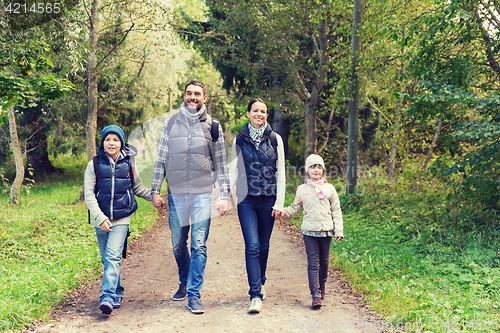 Image of happy family with backpacks hiking in woods