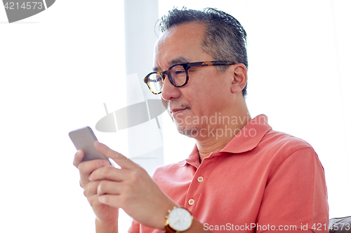 Image of man with smartphone sitting on sofa at home
