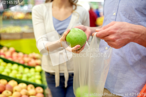 Image of close up of couple buying apples at grocery store