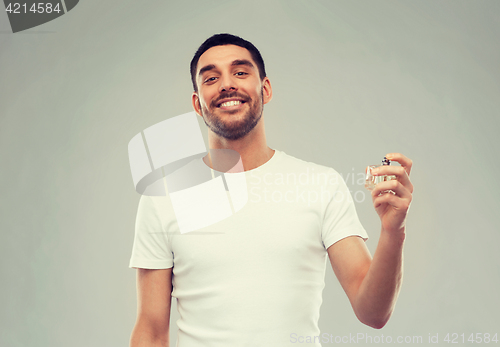 Image of smiling man with male perfume over gray background