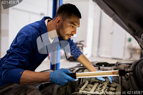 Image of mechanic man with lamp repairing car at workshop