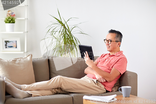 Image of man with tablet pc sitting on sofa at home