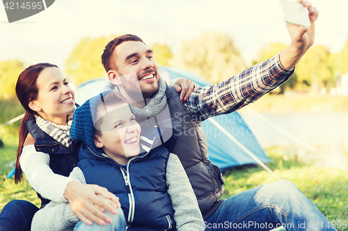 Image of family with smartphone taking selfie at campsite