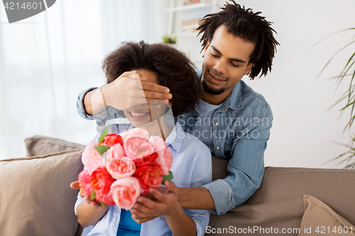 Image of happy couple with bunch of flowers at home