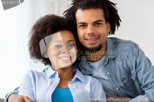 Image of happy couple sitting on sofa and hugging at home