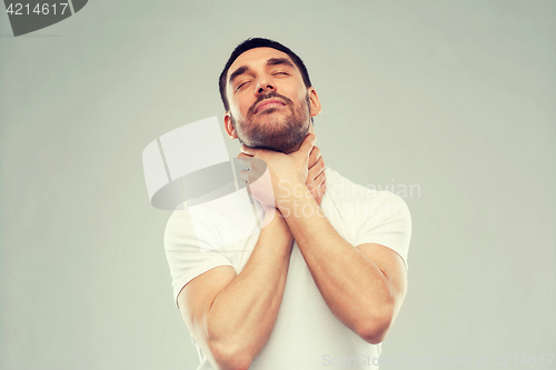 Image of young man choking himself over gray background