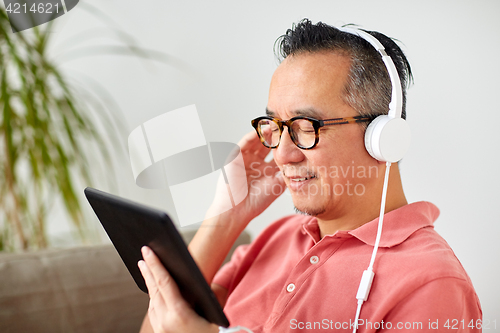Image of man with tablet pc and headphones at home