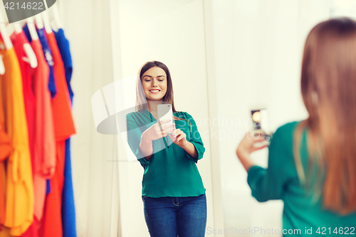 Image of woman with smartphone taking mirror selfie at home