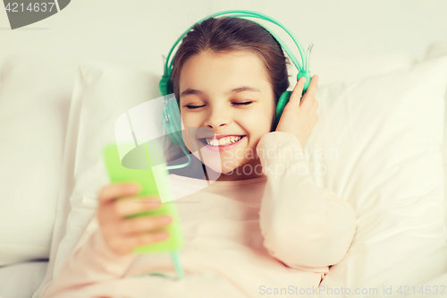 Image of happy girl lying in bed with smartphone at home