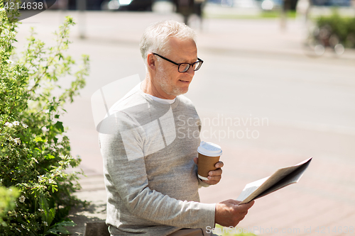 Image of senior man reading newspaper and drinking coffee