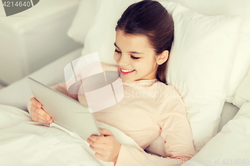 Image of happy girl lying in bed with tablet pc at home